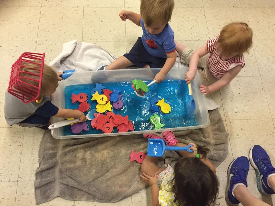 Children playing with water and toys in a sensory bin