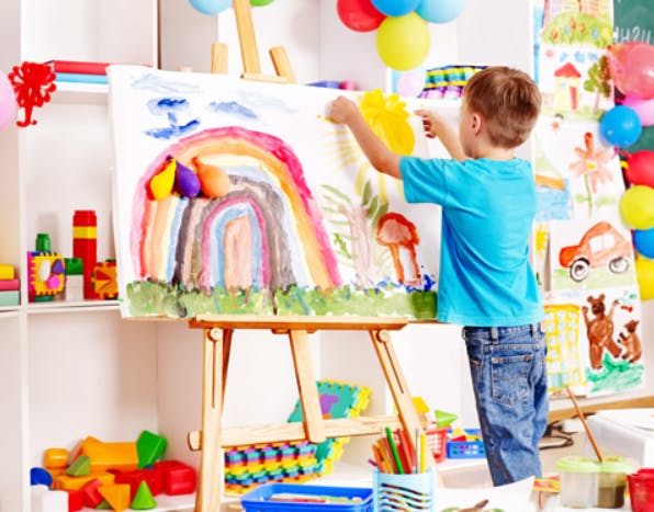 Child painting a rainbow on an easel