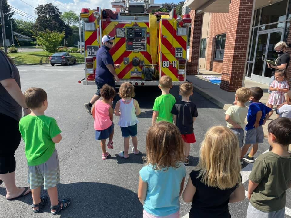 Children gathered around a fire truck with a person standing near the back
