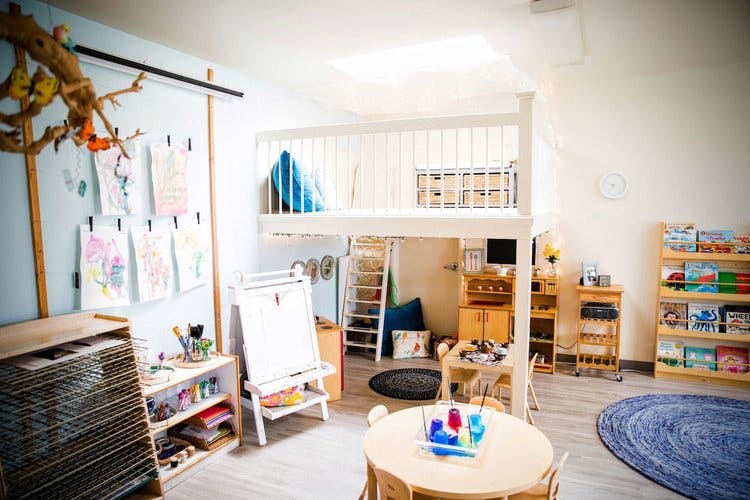 Children's play area with a loft bed, easel, and small tables