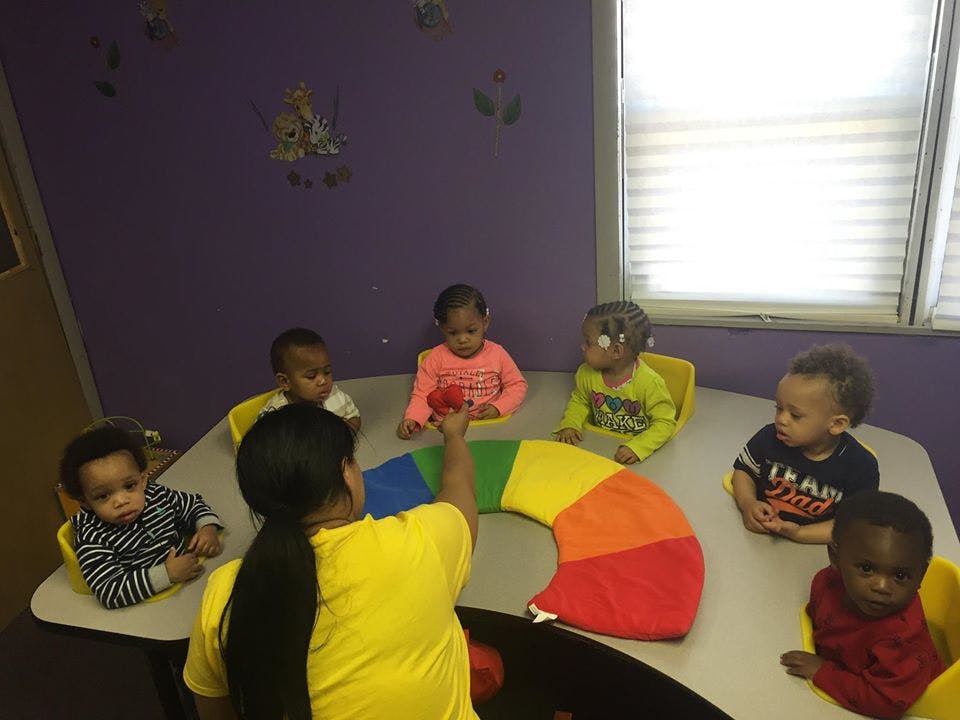 Adult and multiple children sitting around a table with a colorful toy