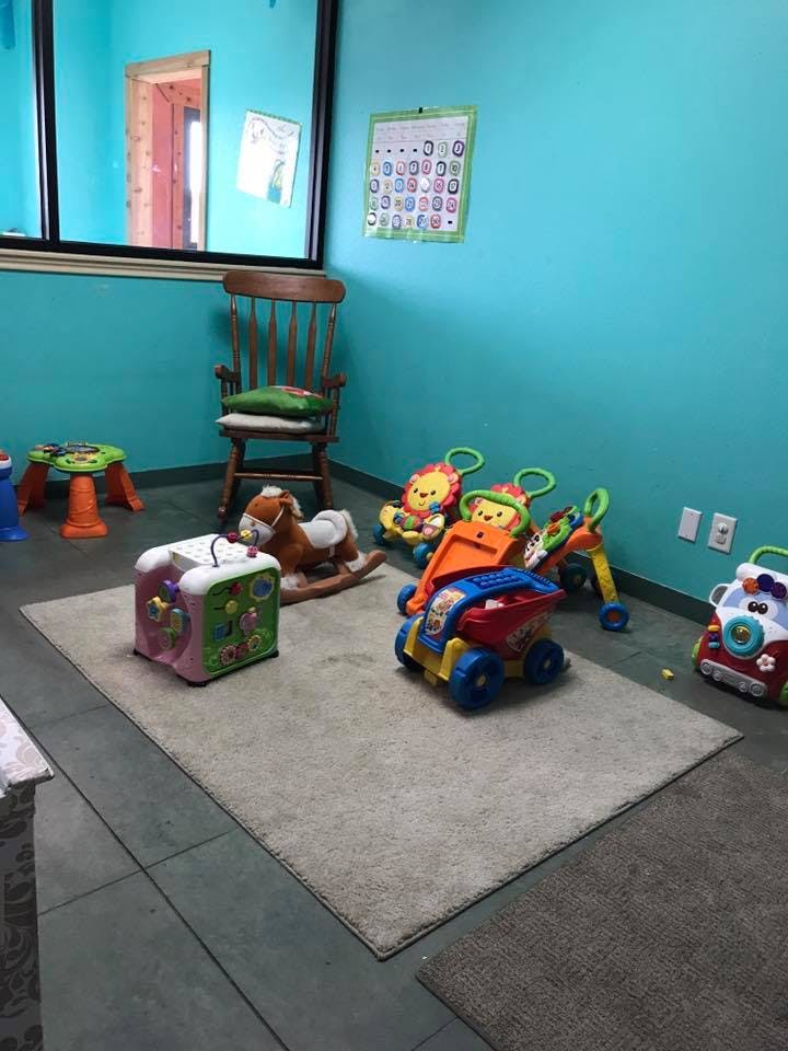 Playroom with various toys on a rug, including a rocking horse and toy trucks