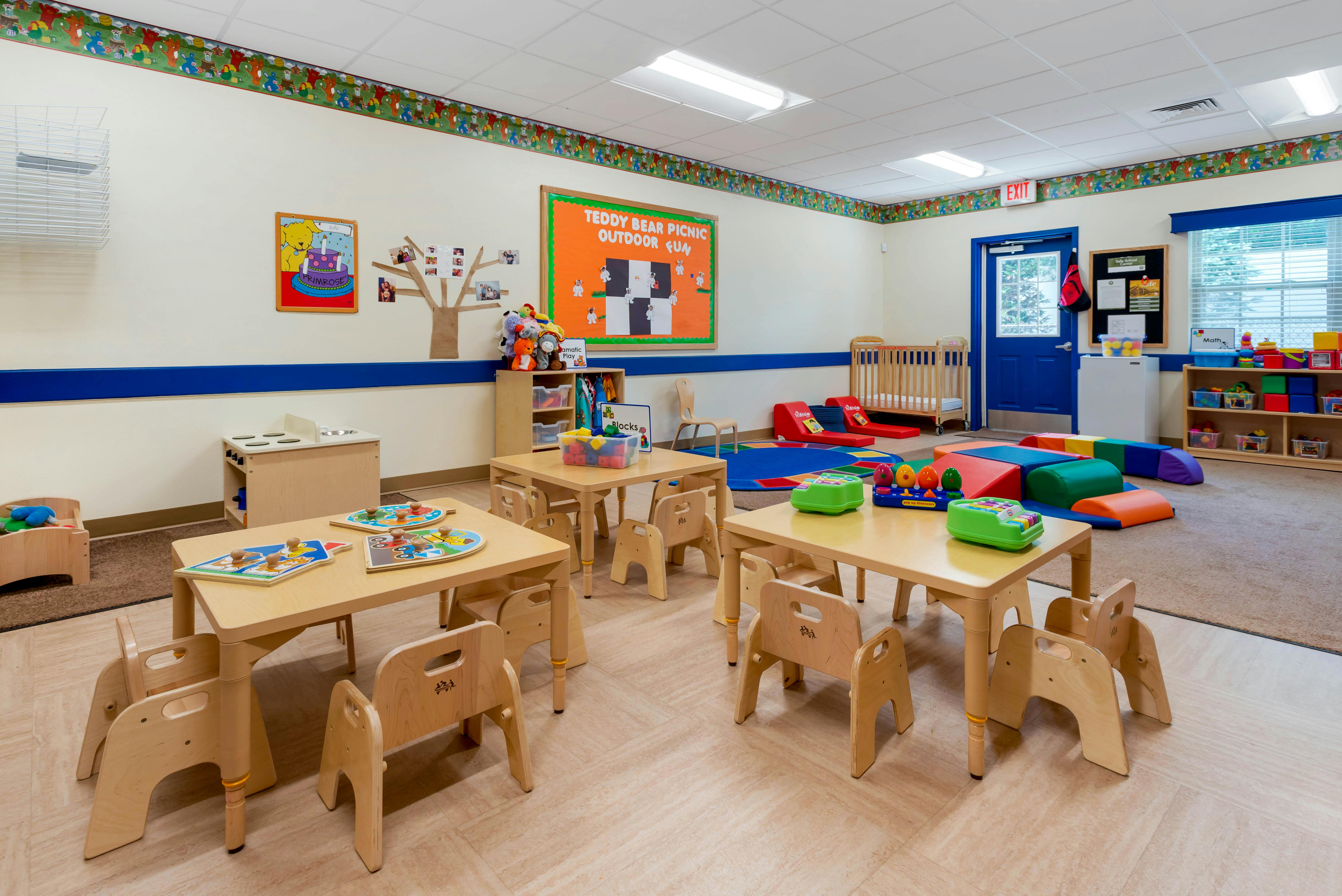 A colorful empty classroom with small wooden tables and chairs