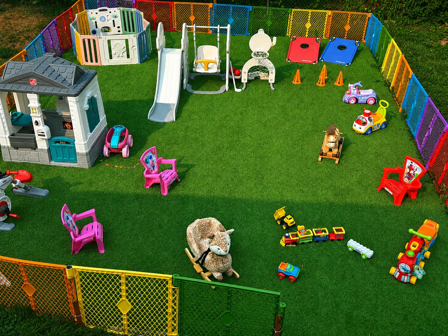 Outdoor children play area with plastic playhouse slide swing and ride-on toys