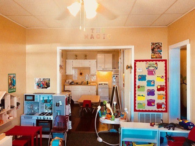 Playroom with toy kitchen and calendar, kitchen visible through doorway