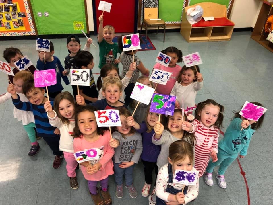 Group of children holding up signs with the number 50