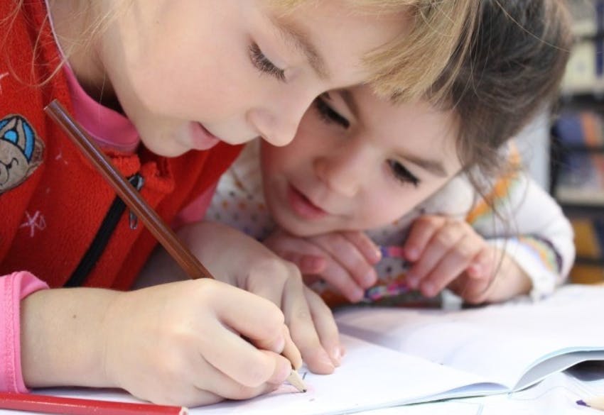 Two children writing in a notebook