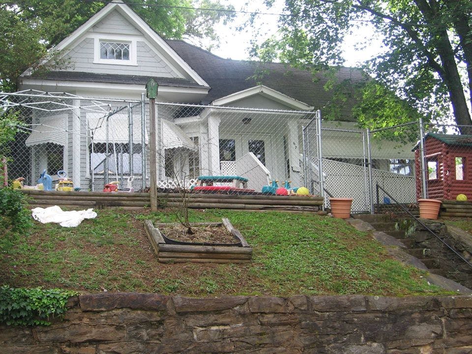 House with a fenced-in yard on a grassy hill