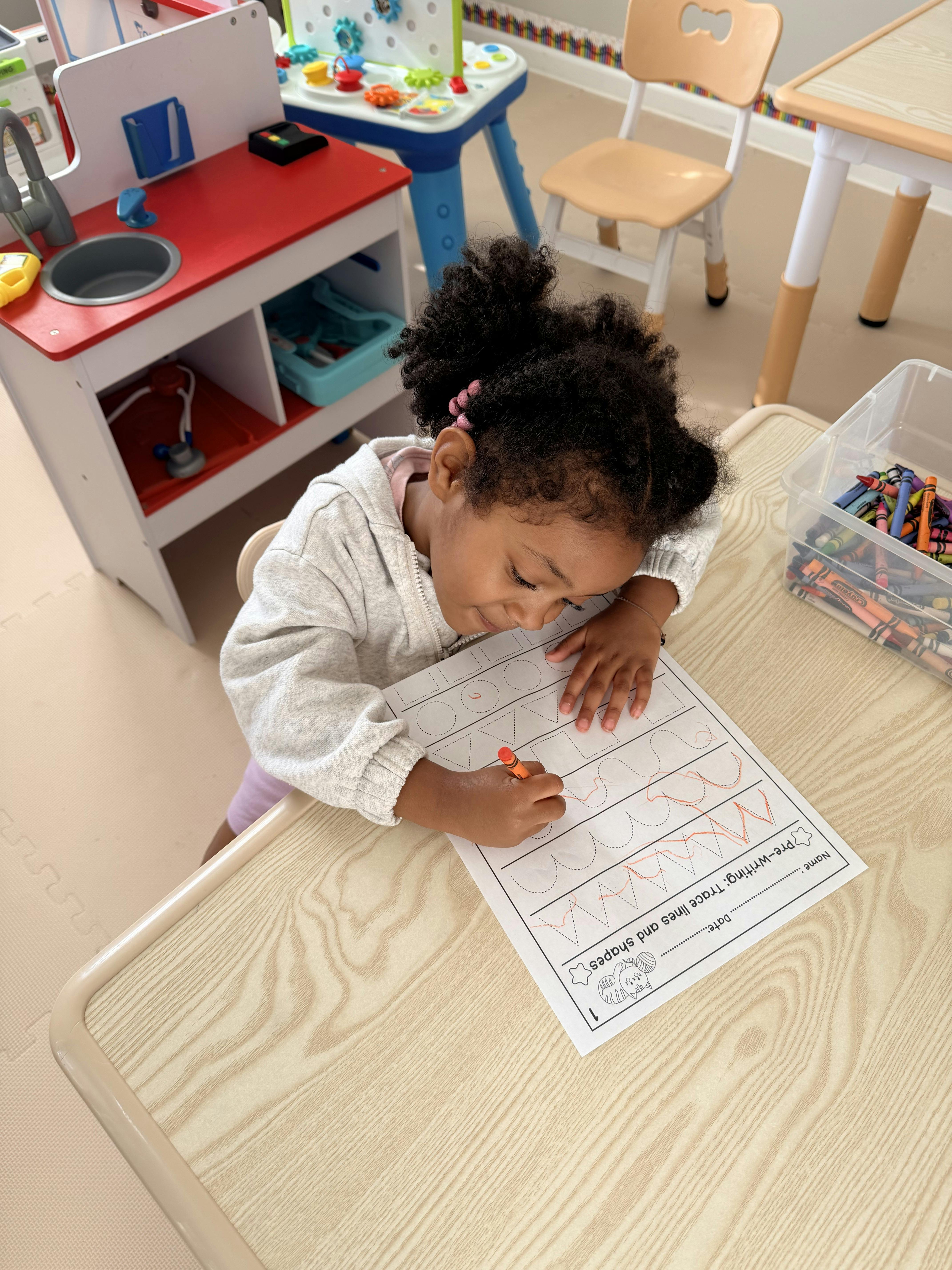 Child tracing lines and shapes on a worksheet at a table