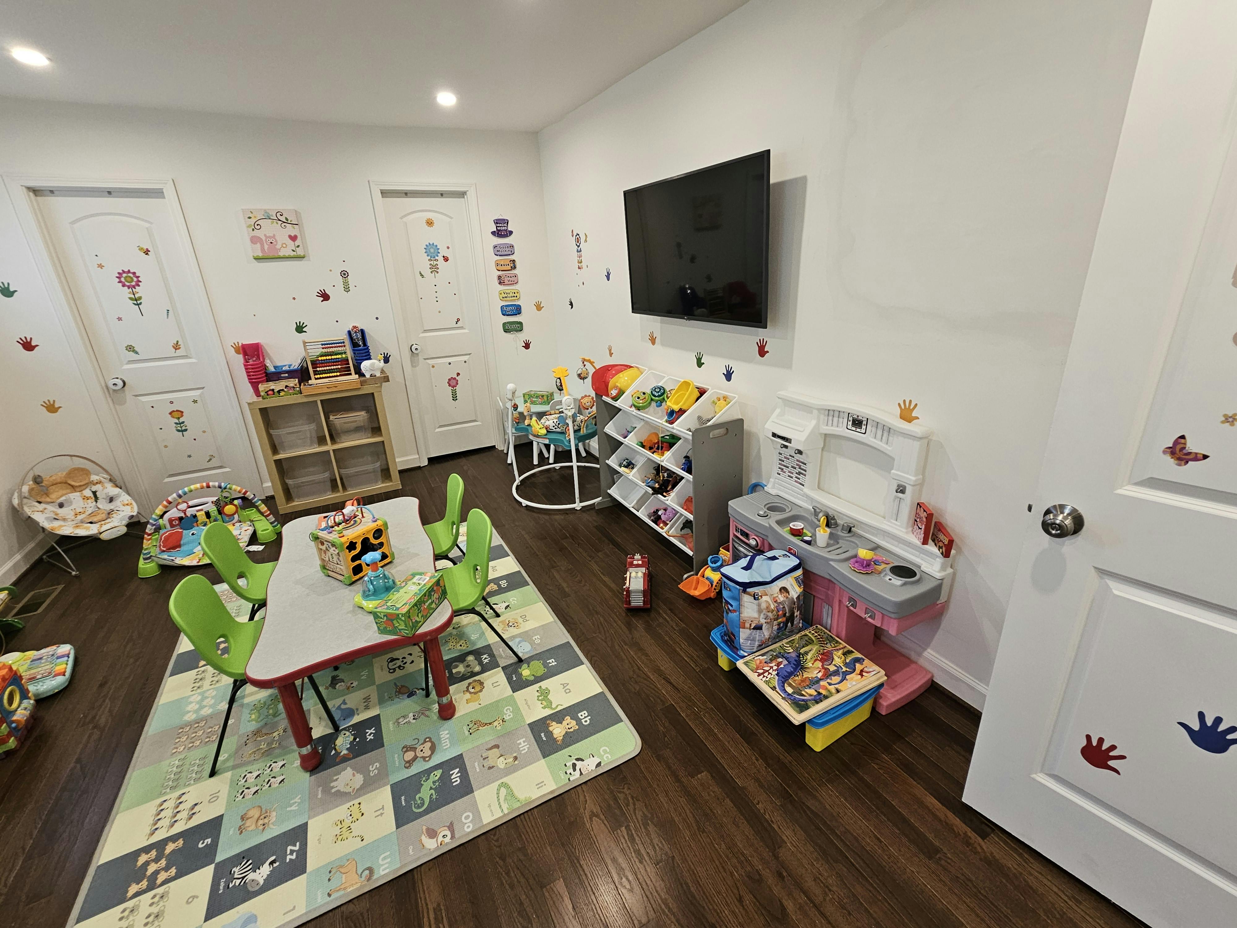Children's playroom with a table, chairs, play kitchen, and assorted toys