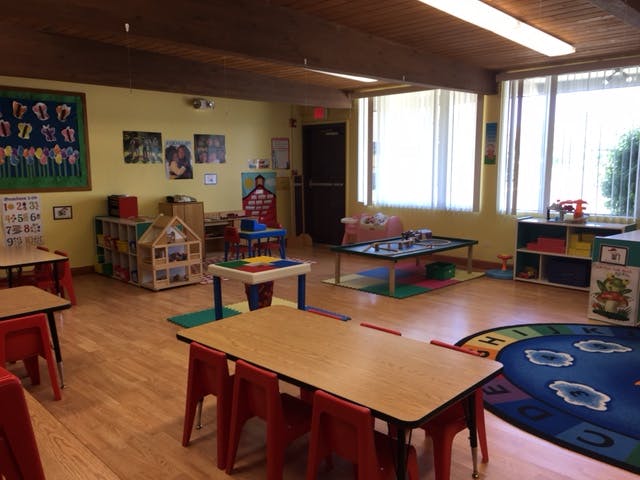 Classroom with small tables and chairs, play areas, and windows