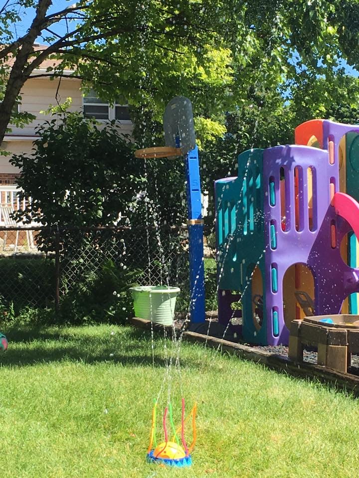 Water sprinkler and playground equipment in a grassy yard