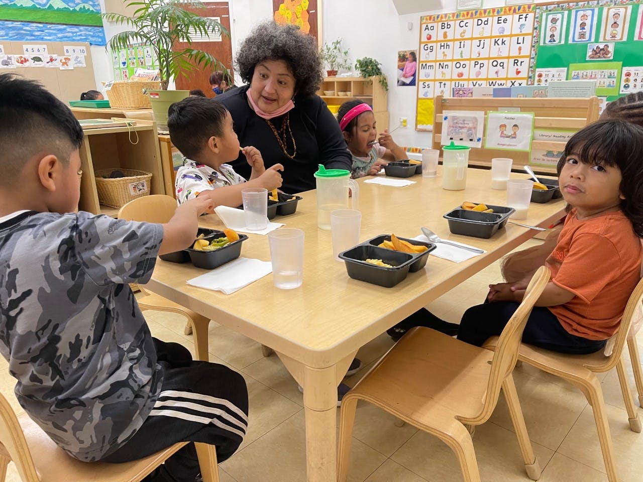 Adult and children eating at a table in a classroom