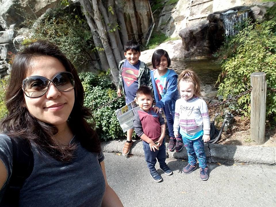 Person in sunglasses taking a selfie with four children behind them