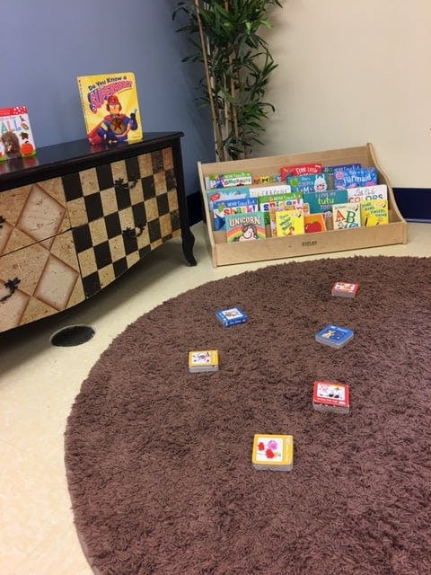 Children's books on a shelf and a rug with small boxes