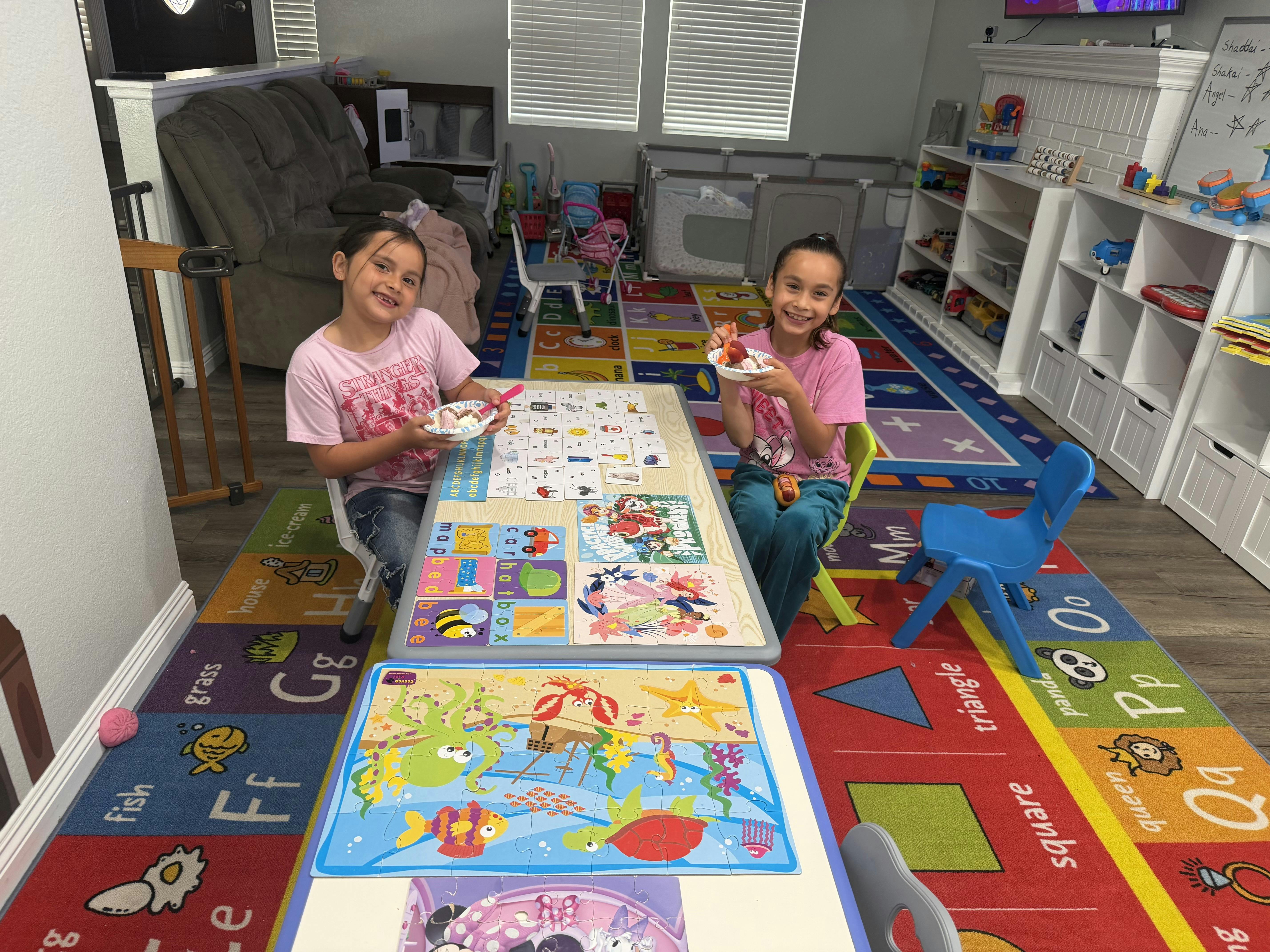 Two children sitting at tables doing puzzles in a play area