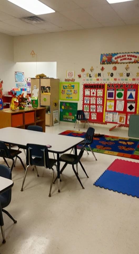 Classroom with tables, chairs, and educational posters on the wall