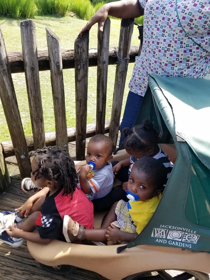 Person standing behind a wooden fence with children in a stroller
