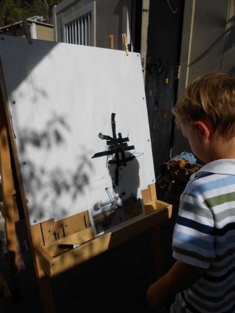 Child looking at a white board with a black abstract shape