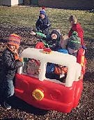 Children playing on a toy fire truck outdoors