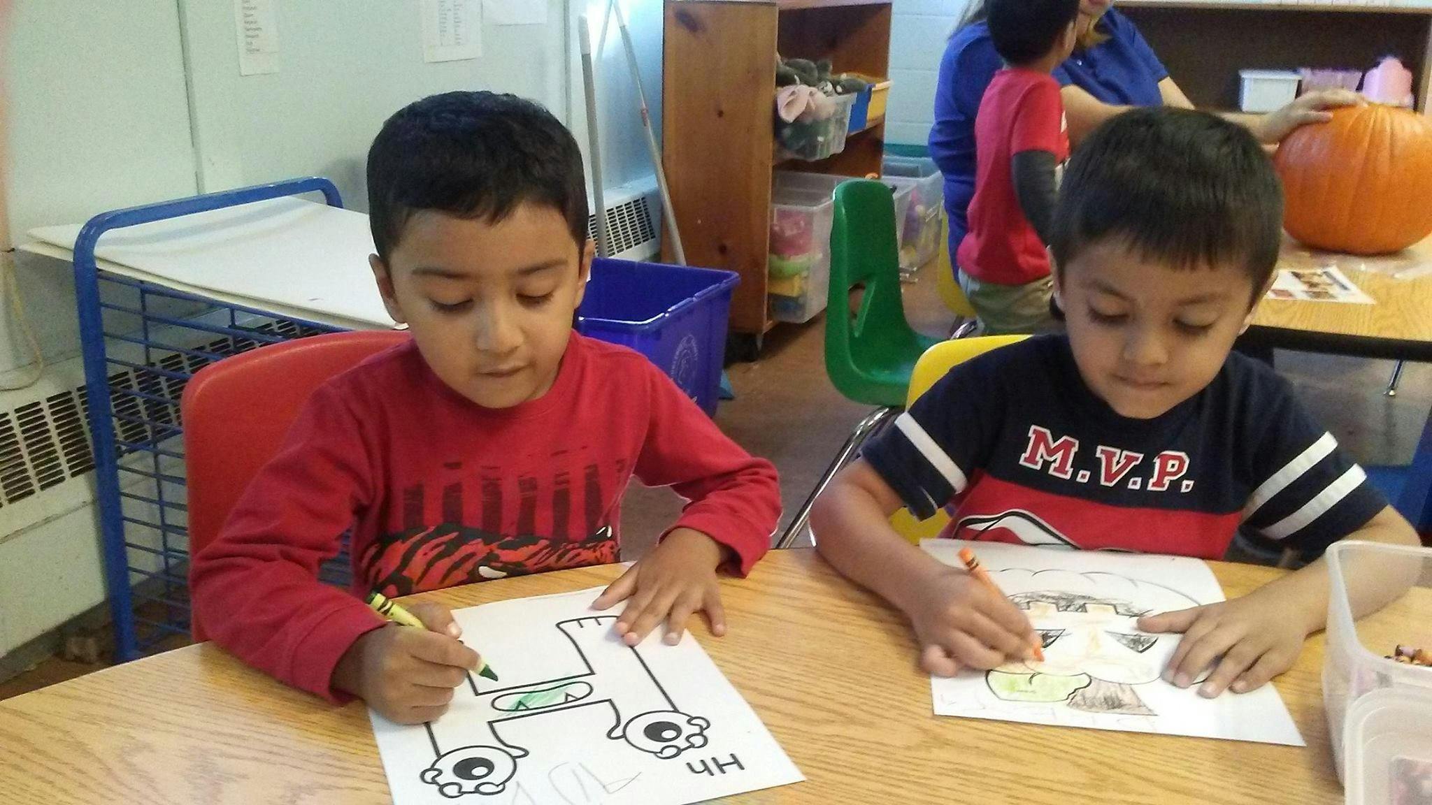 Two children coloring at a table in a classroom