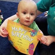 Child holding a birthday card that says "Happy Birthday"