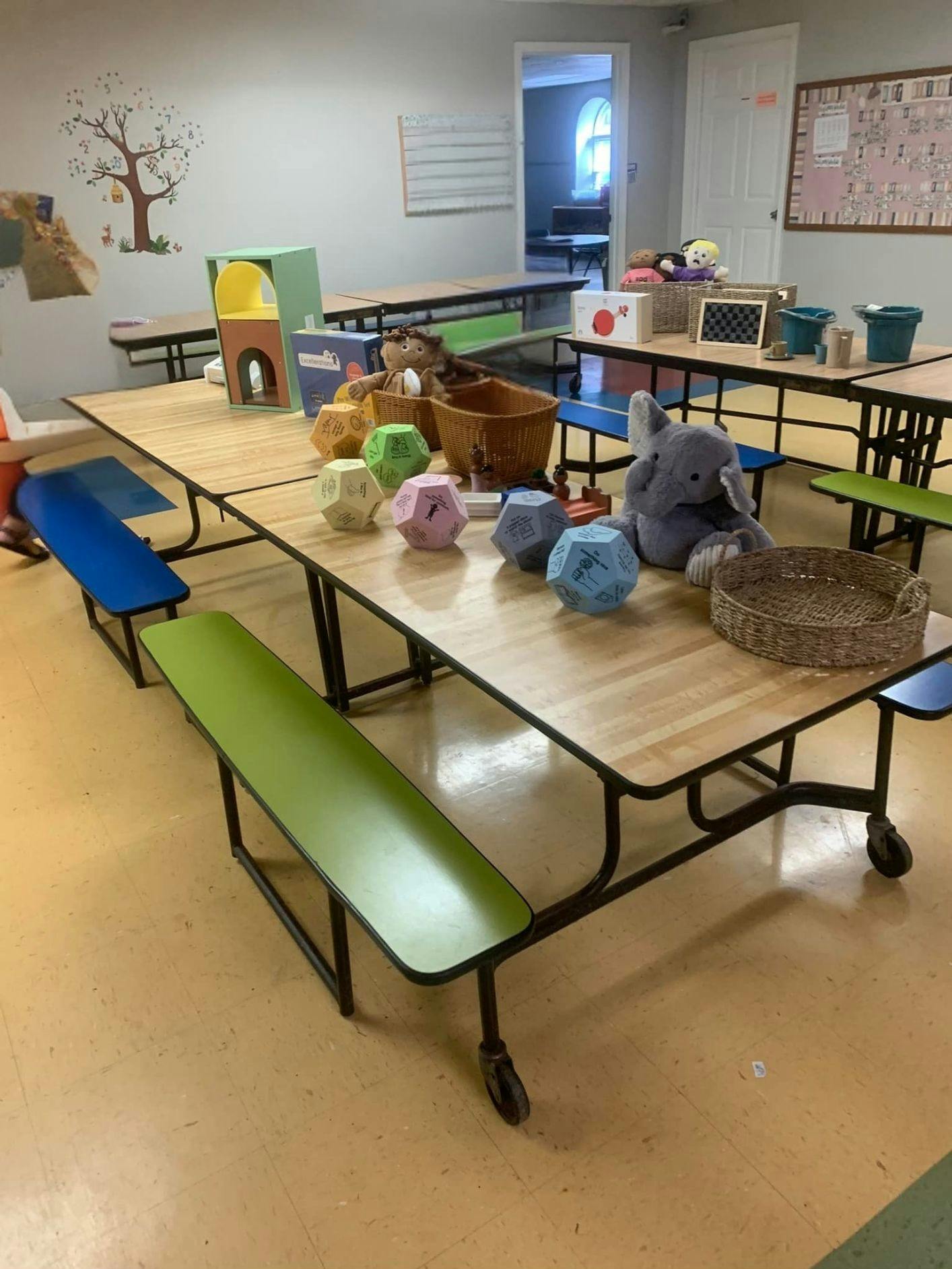 Classroom with long tables and benches, with toys and educational items on tables