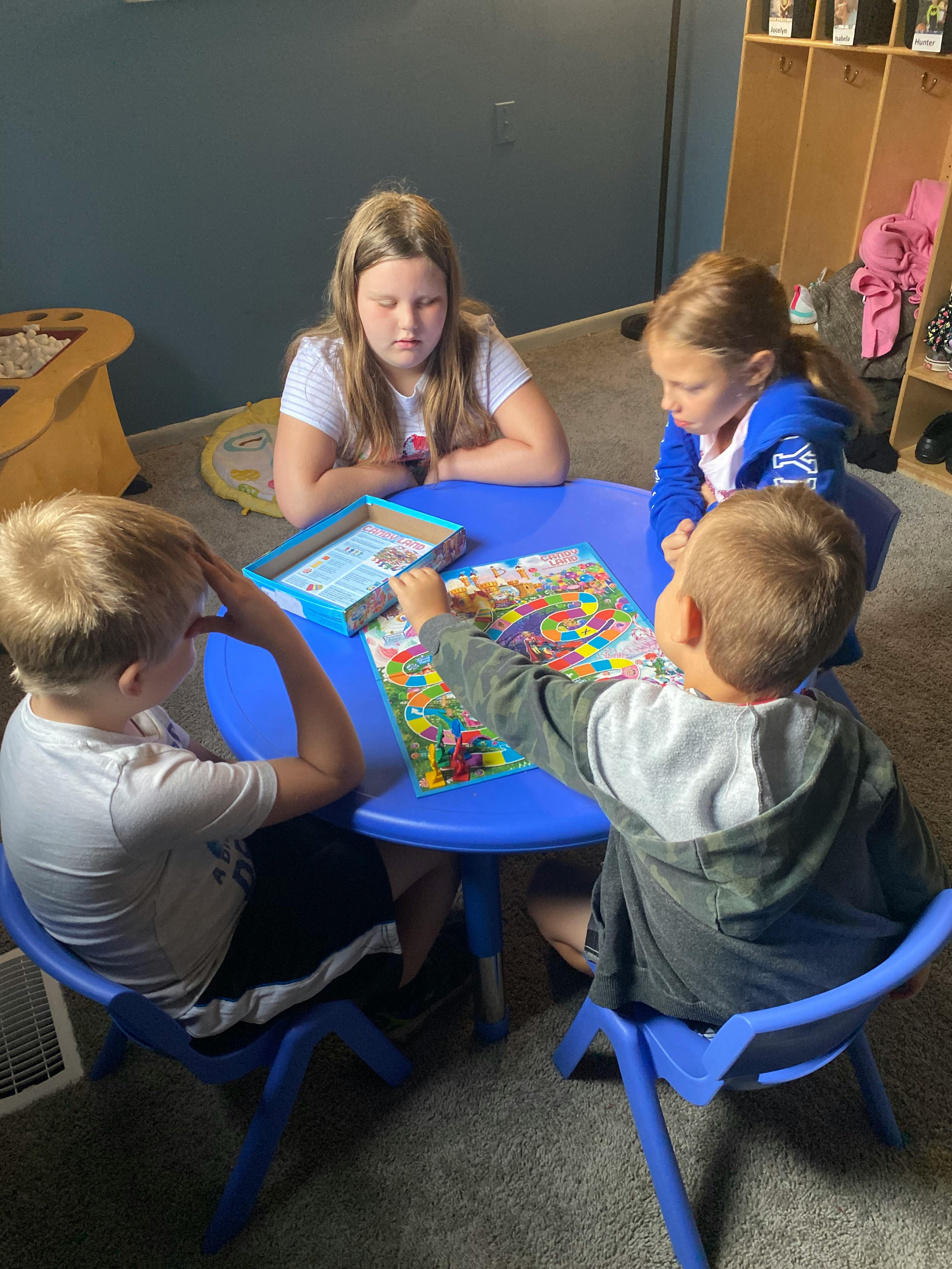 Four children playing a board game at a blue table