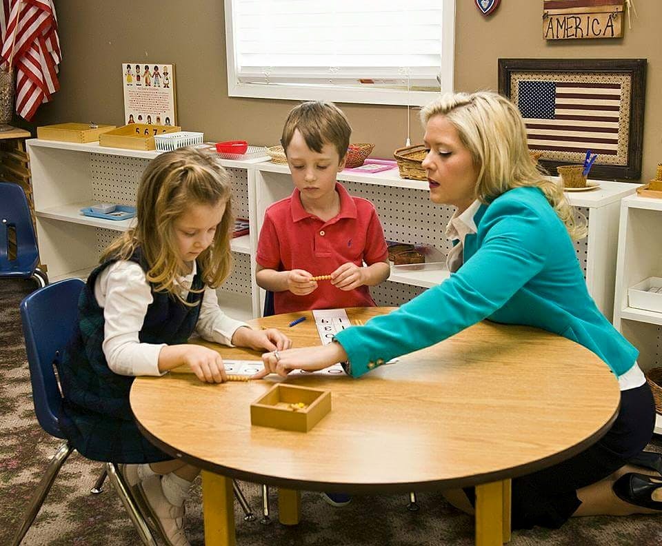 Adult and two children at a table in a classroom