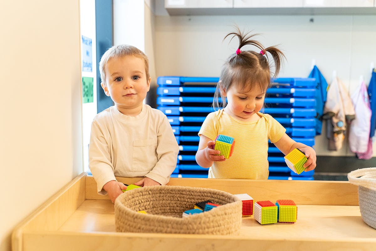 Two children playing with colorful blocks in a classroom