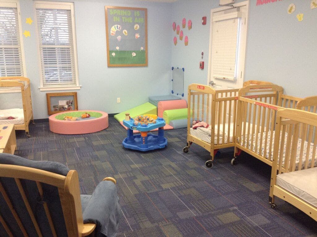 Room with multiple cribs, play mat, and soft play equipment