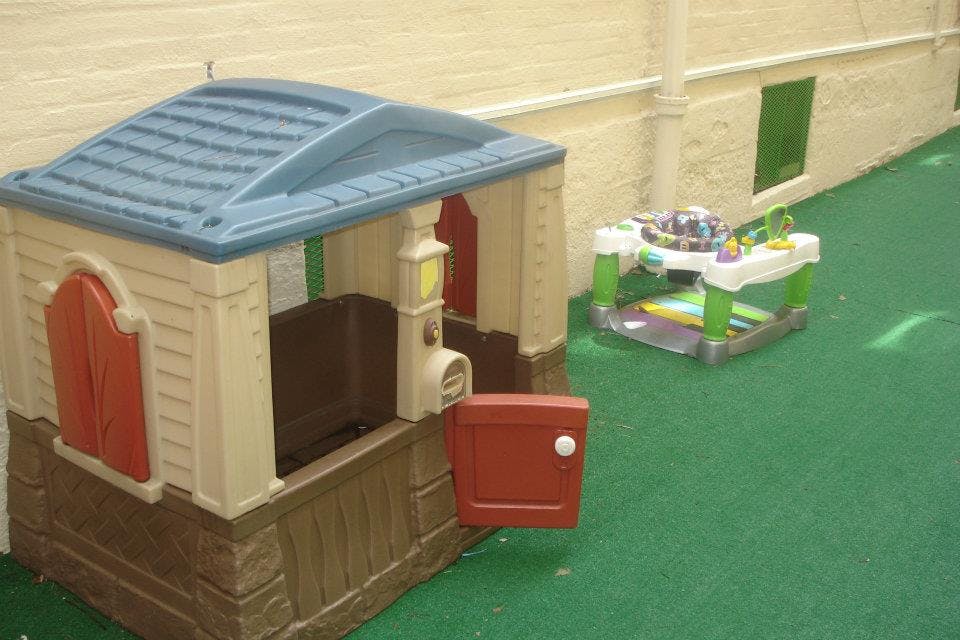 Plastic playhouse and baby activity center on green carpet
