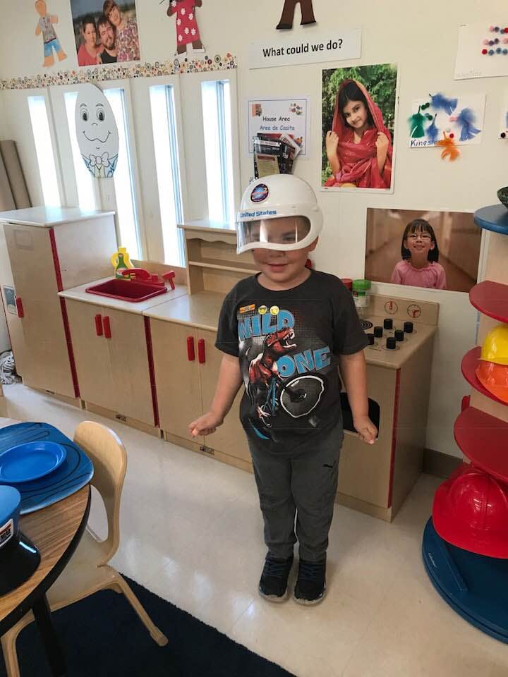 Child wearing a white helmet in a classroom