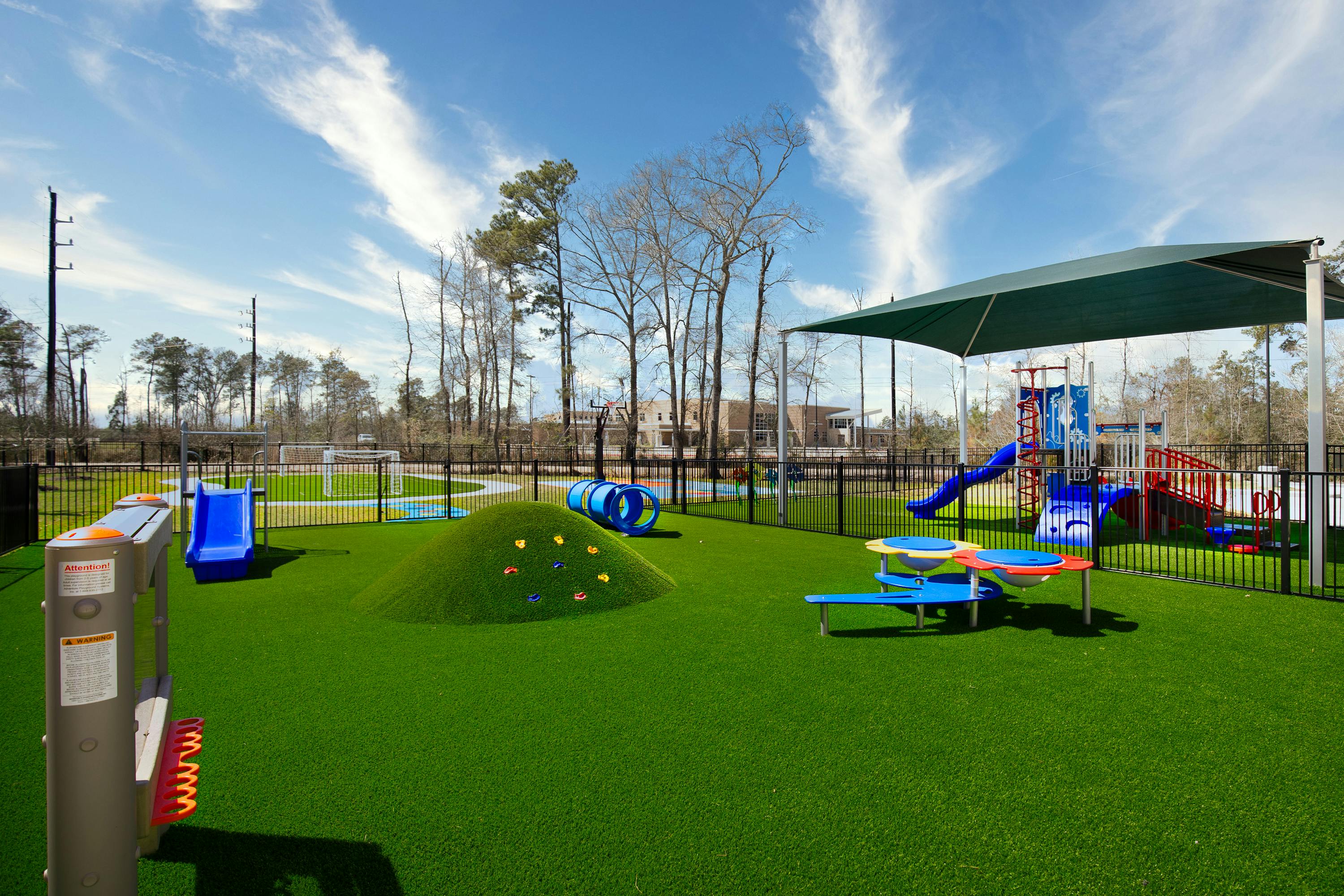 Playground with artificial turf, slides, tunnels, and a shaded play structure