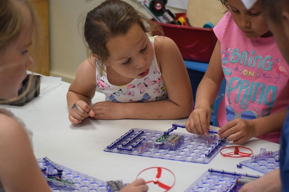 Children assembling electronic components on a board
