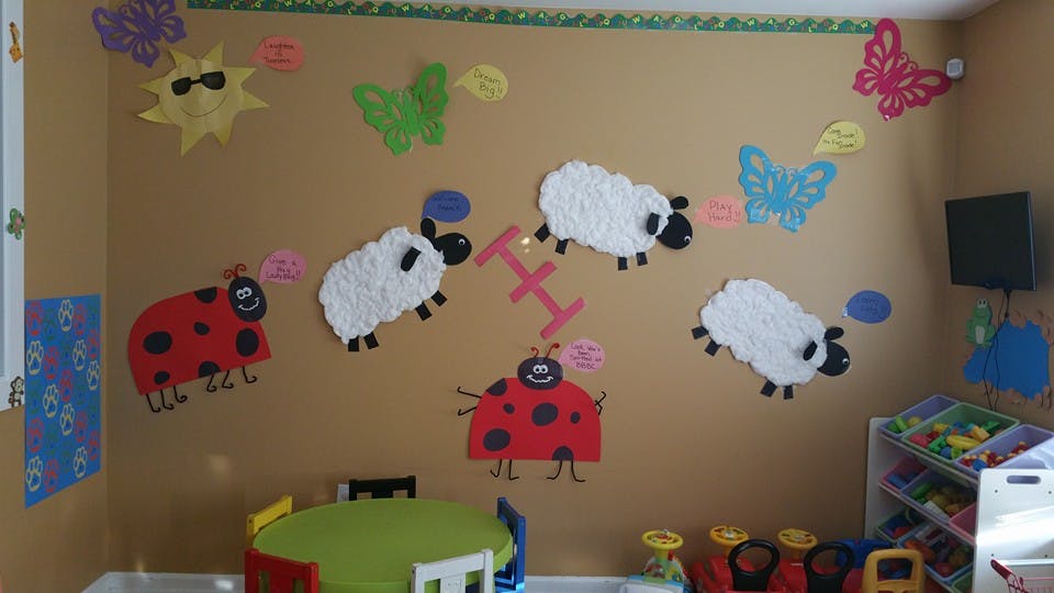 Wall decorated with cutouts of sheep, ladybugs, sun, and butterflies