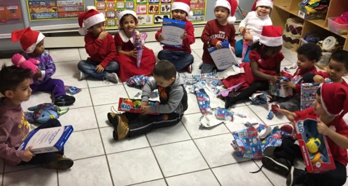 Children in Santa hats opening gifts on the floor