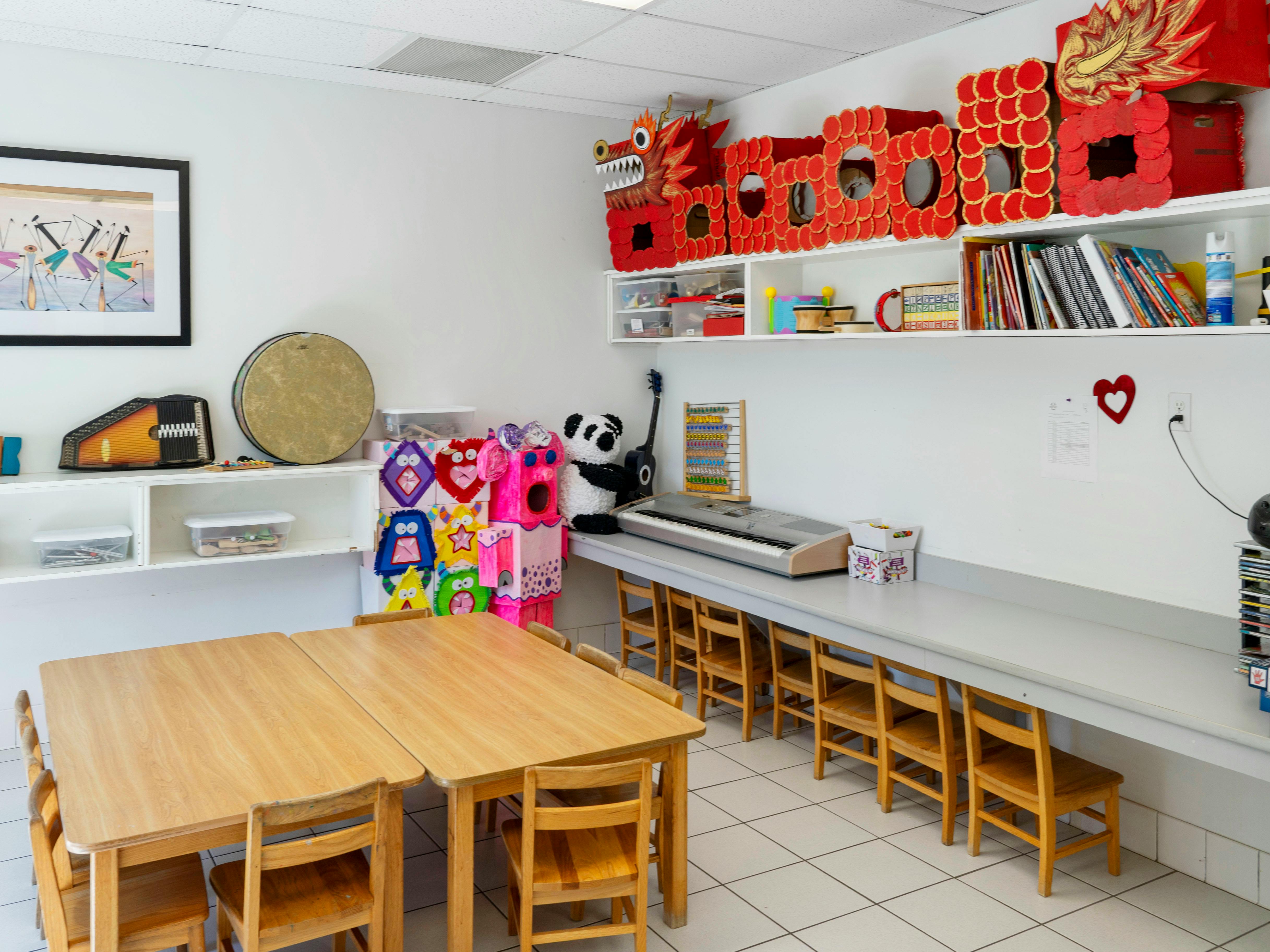 children's classroom with tables, chairs, shelves of supplies, and a red dragon decoration