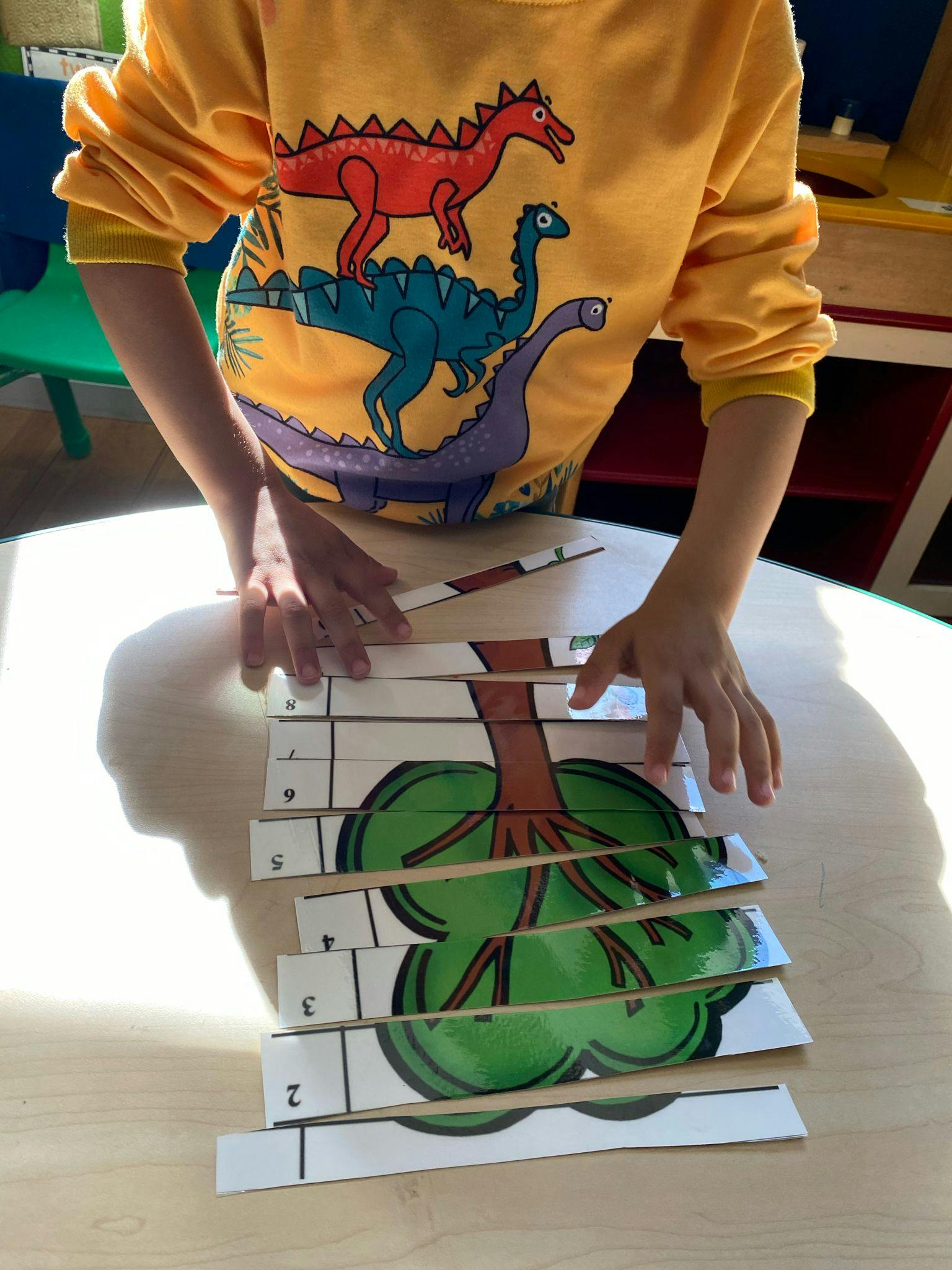 Child assembling a tree puzzle on a table