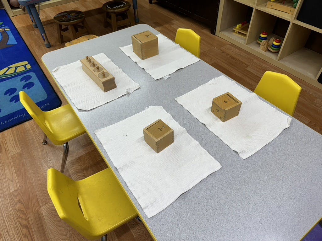 Wooden manipulative toys on white placemats on a classroom table