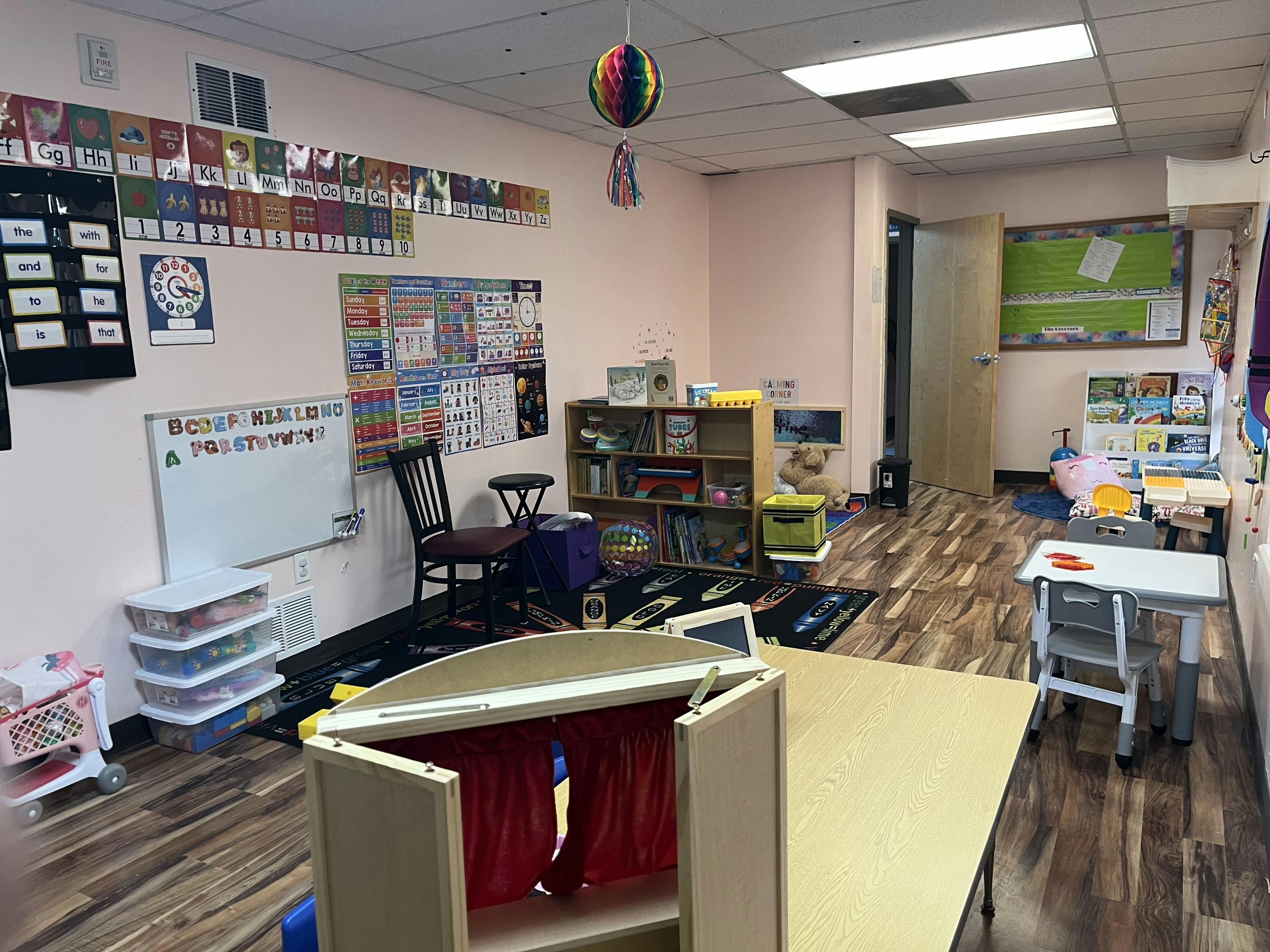 Classroom with educational posters, a small table and chairs, and a puppet theater