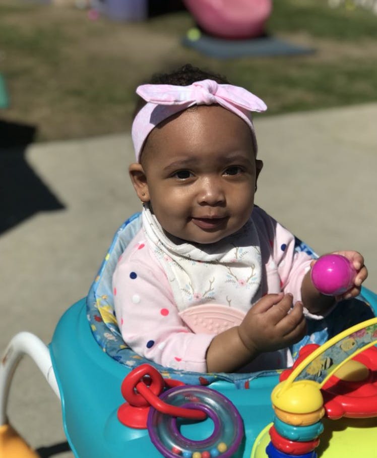 Child in a baby walker holding a pink ball