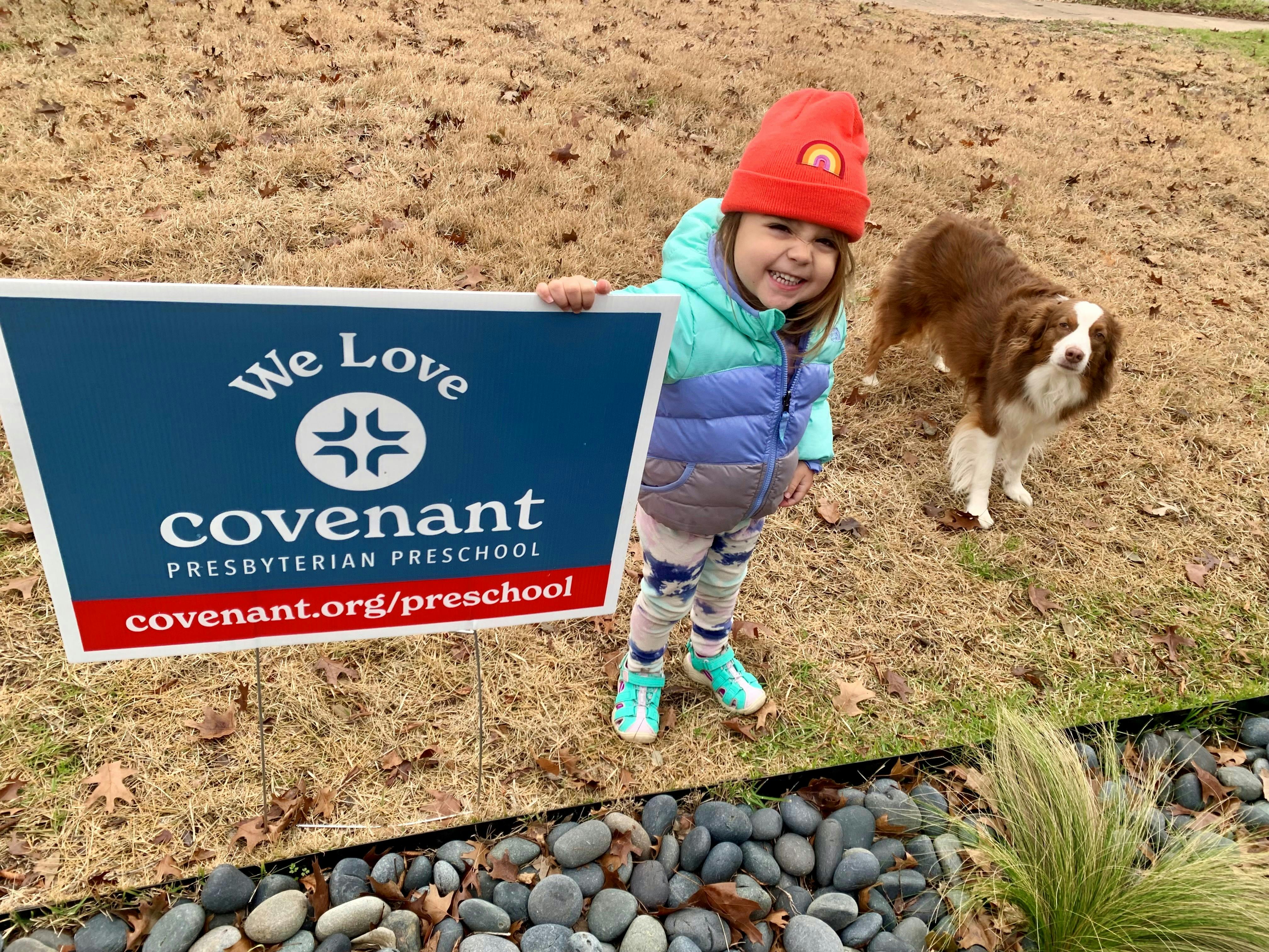 Child holding a sign for Covenant Presbyterian Preschool with a dog nearby