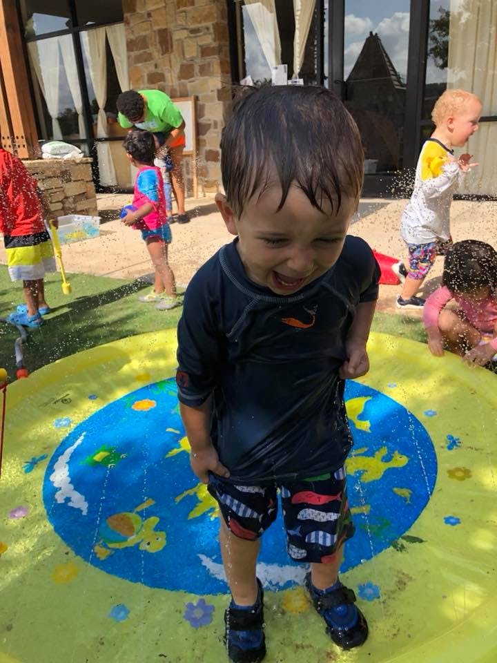 Child in wet clothes standing on a splash pad