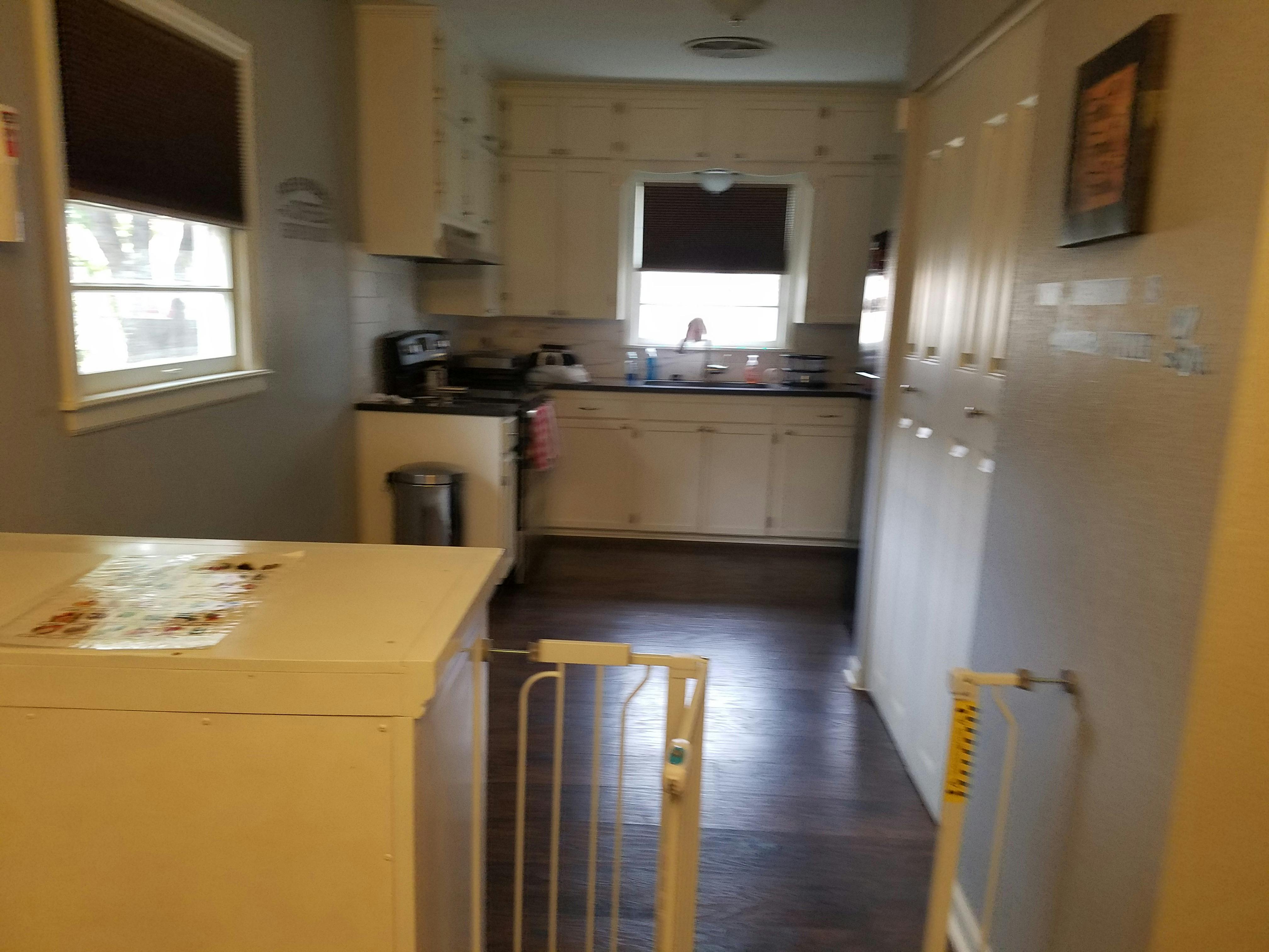 Kitchen with white cabinets, dark floor, and baby gate