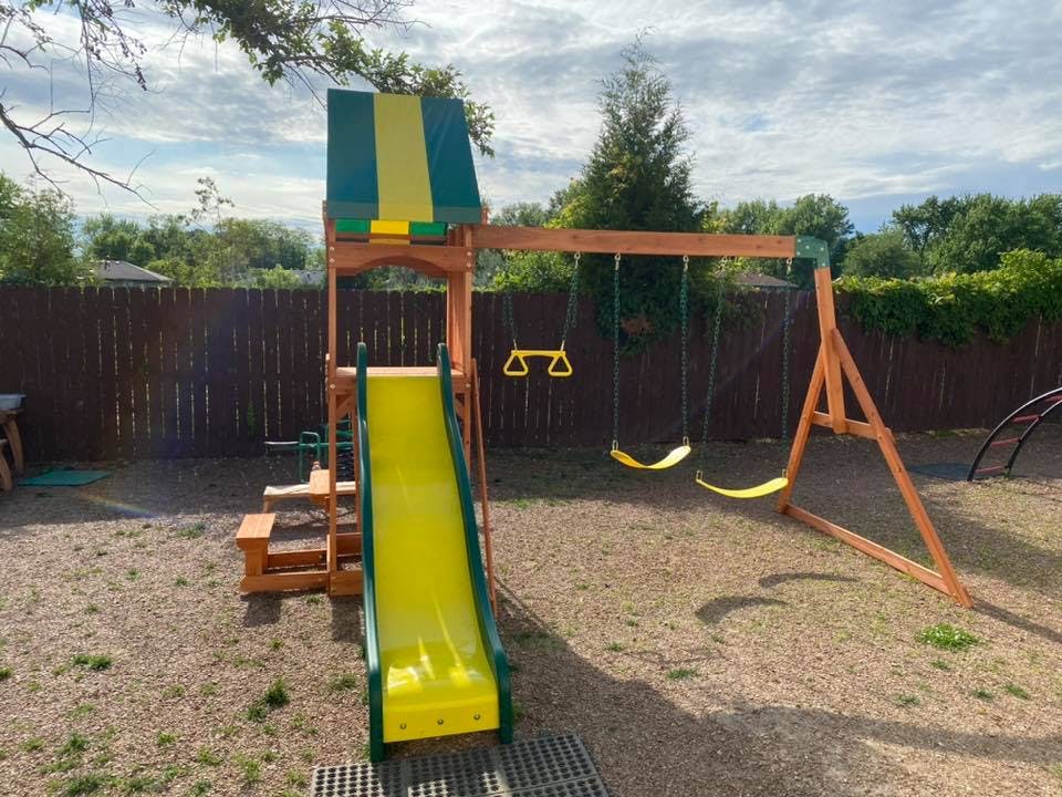 Wooden playground set with a yellow slide and swings