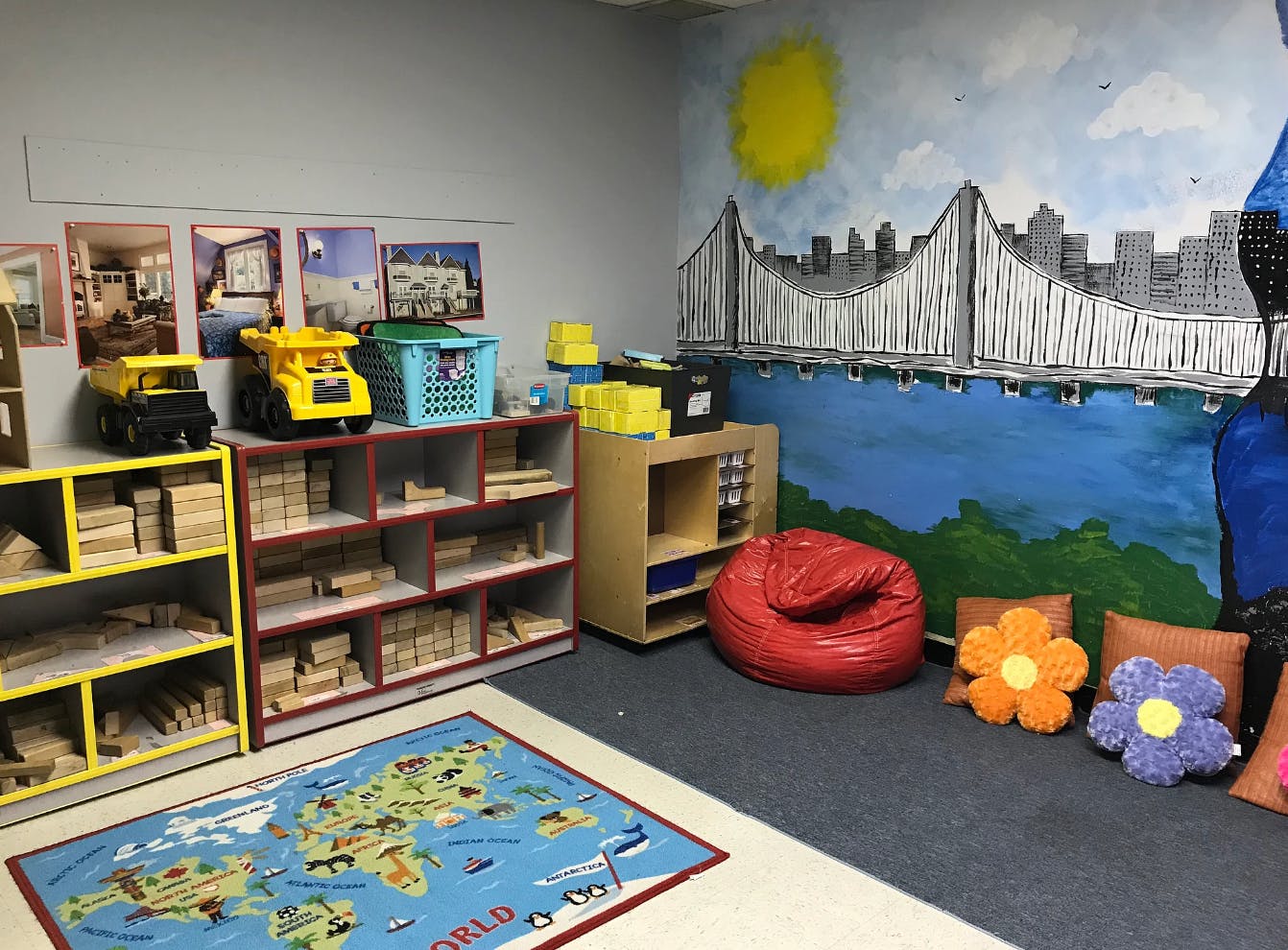 Classroom with shelves of toys, a world map rug, and a mural of a bridge