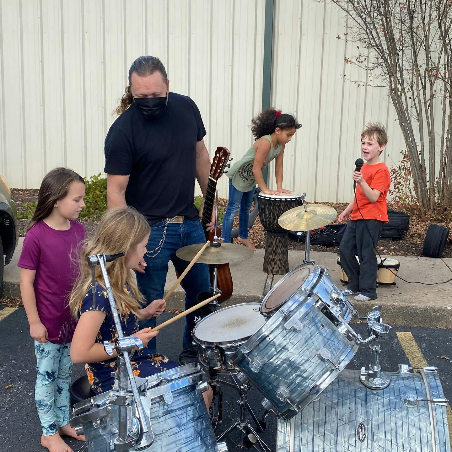 Person with children playing drums and singing outdoors