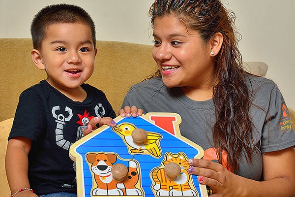 Person and child holding a wooden animal puzzle