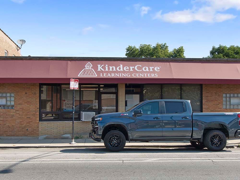 gray pickup truck parked in front of a brick building with a KinderCare sign